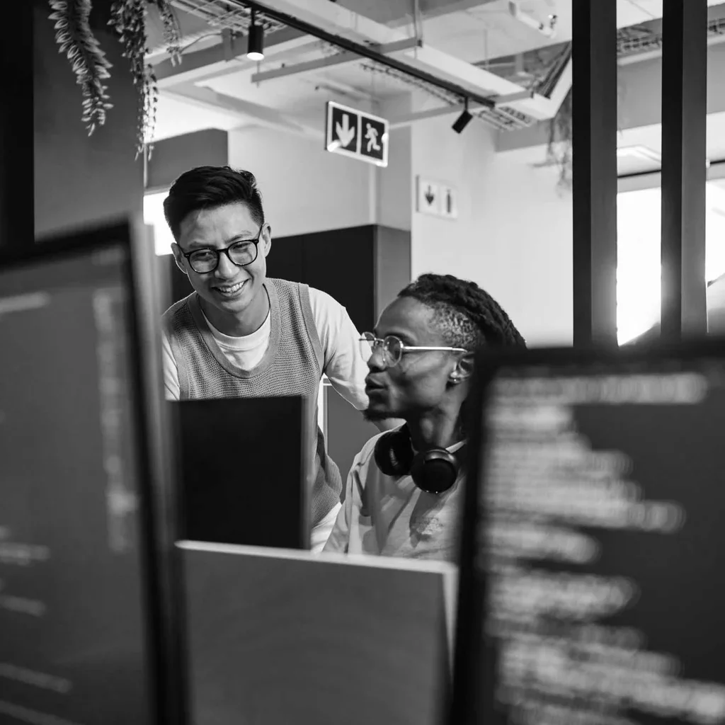 Two cybersecurity professionals collaborating at computer monitors