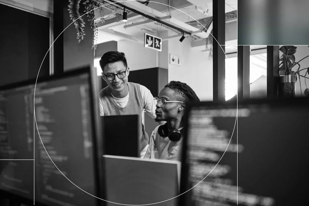 Cybersecurity professionals collaborating at computer monitors in a modern office