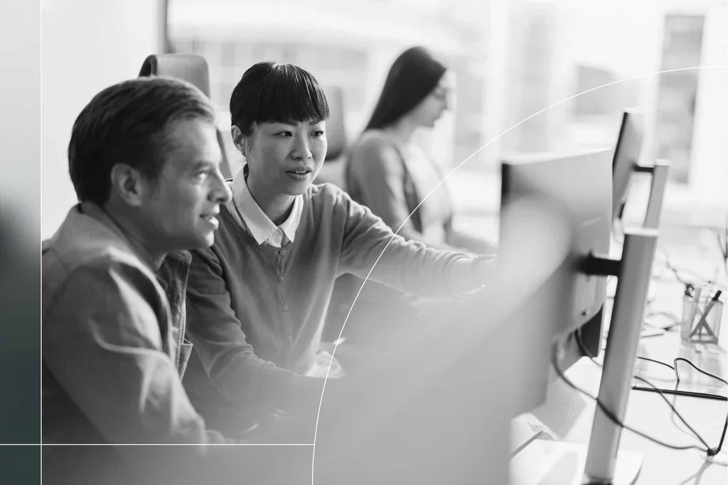 Two IT professionals reviewing security systems on multiple monitors