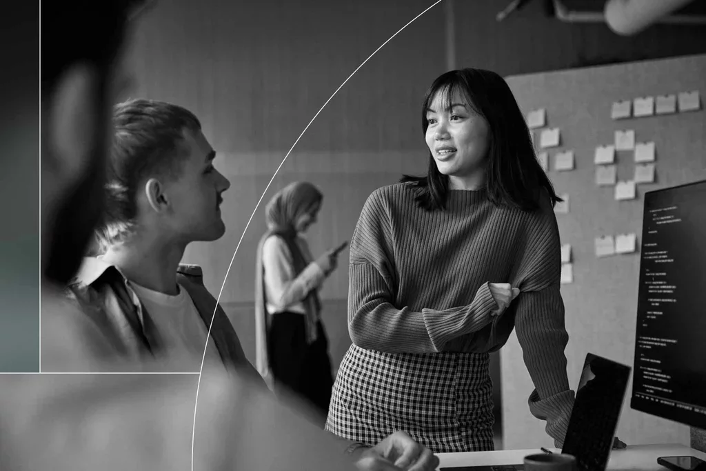 Colleagues discussing cybersecurity work beside a computer monitor