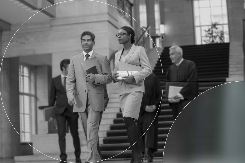 Two government professionals walking through a courthouse while carrying documents.