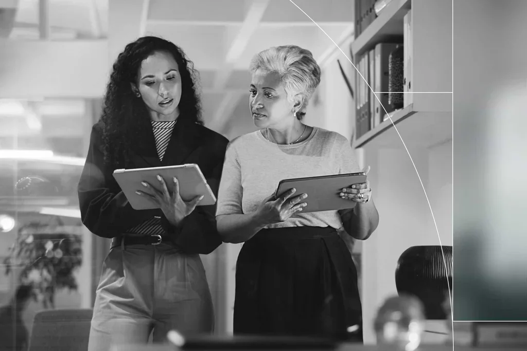 Two professionals review information on tablets while working together.