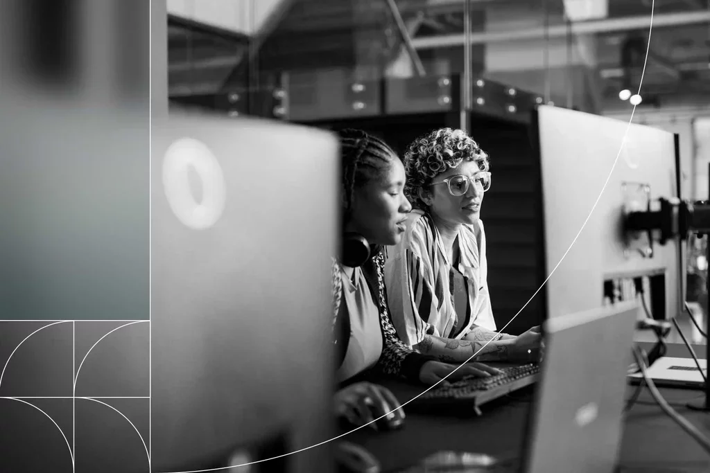 Two cybersecurity analysts collaborating at computer workstations.