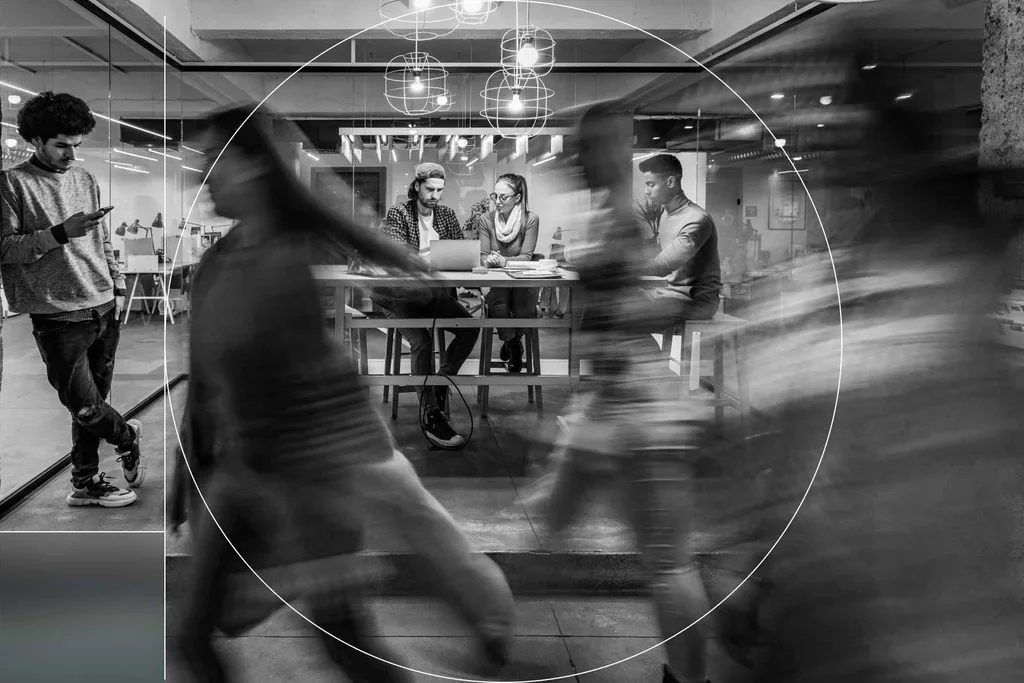 Employees work and collaborate in a busy open office environment.