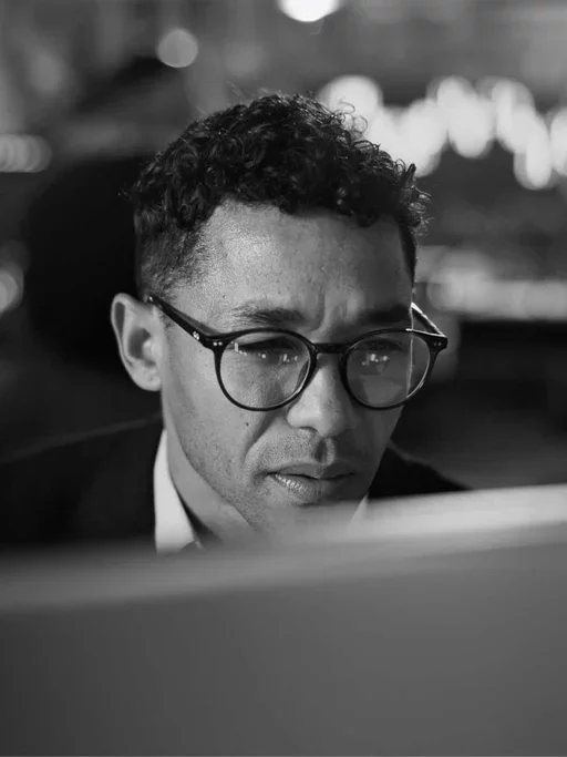 Business professional focuses on a computer screen while monitoring digital activity.
