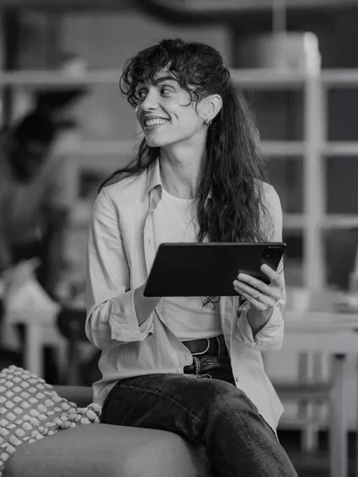 Professional holds a tablet while collaborating with colleagues in an office.