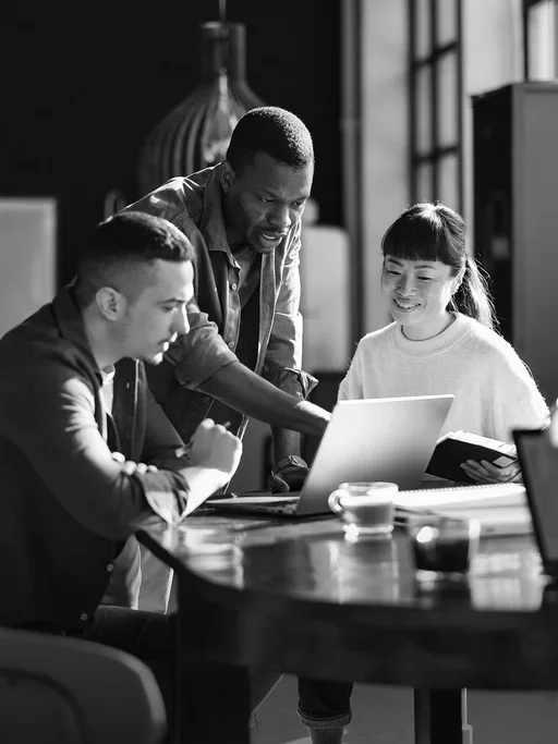 Three enterprise professionals collaborating around a laptop to review data security posture management insights and cloud data protection strategies.