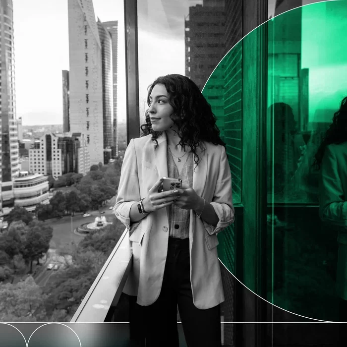 Business professional using a smartphone while walking through a modern office.