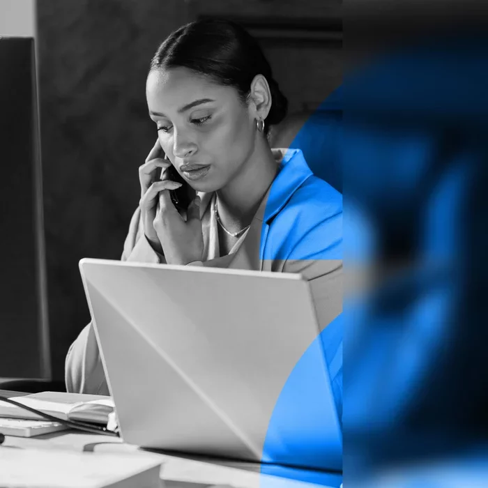 Business professional working on a laptop while speaking on a phone.