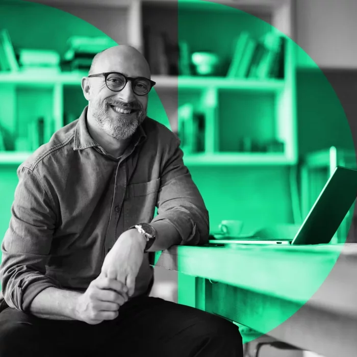 Professional seated beside a laptop in a modern office workspace