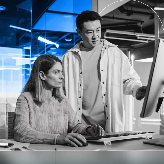 Two security professionals reviewing information on a computer monitor.