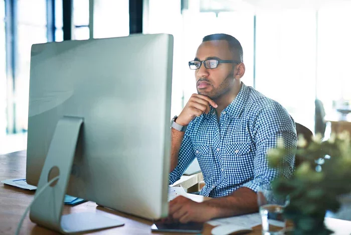 Professional analyzing data on desktop computer in office workspace.