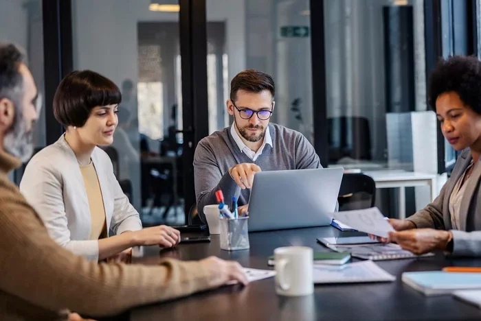 Team reviewing documents and laptop data during business meeting.