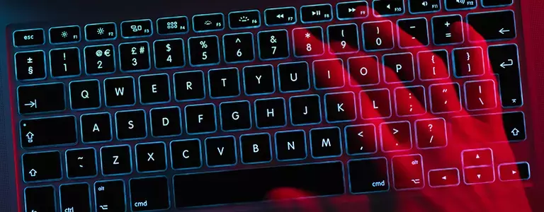 Red hand typing on a computer keyboard