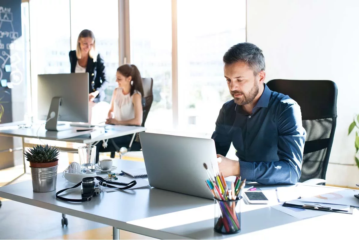 Professional working on laptop in bright office environment.