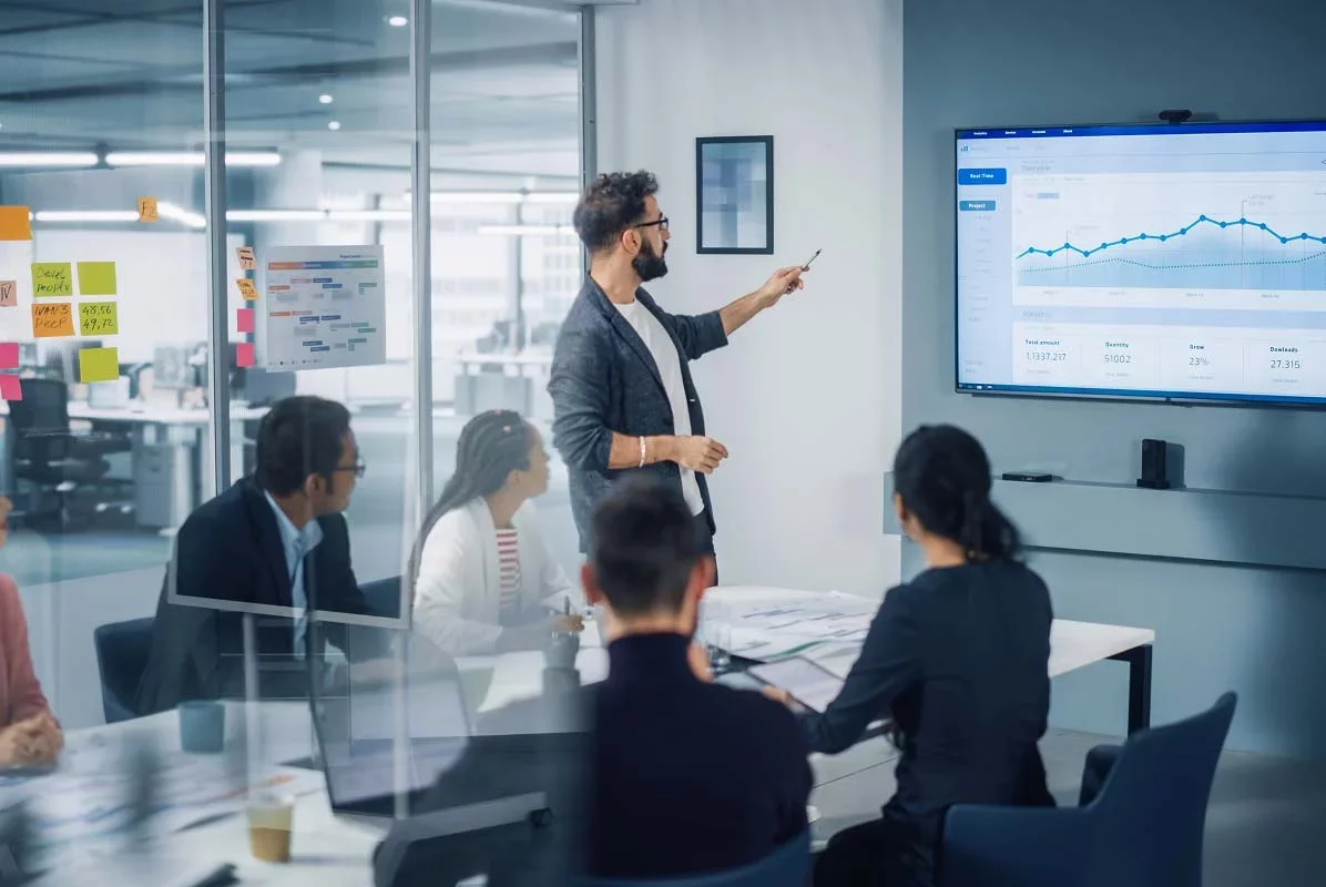 Presenter reviewing analytics dashboard with team during business meeting.