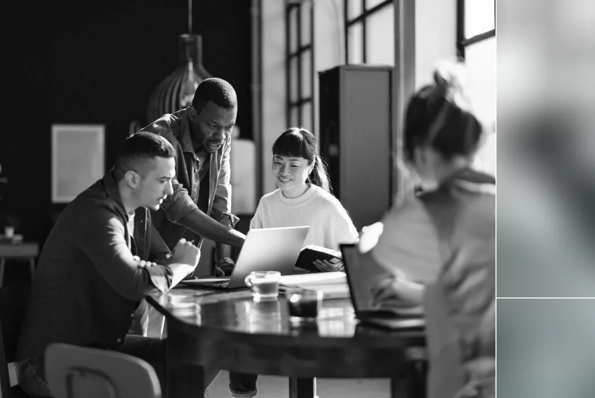 Team members collaborating around a laptop during a meeting in a modern office.