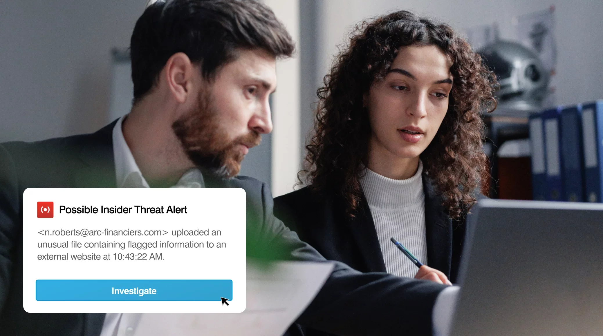 Zwei Personen besprechen eine Proofpoint-Sicherheitswarnung auf einem Laptop