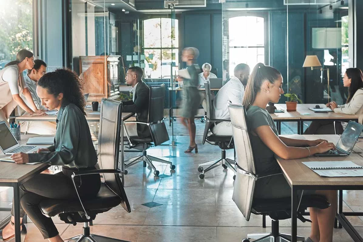 Open office team working on laptops and collaborating across desks.