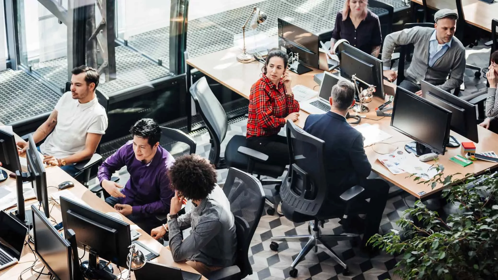 Open office team working across multiple desktop monitors.