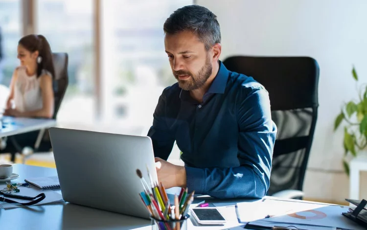 Professional working on laptop in modern office environment.