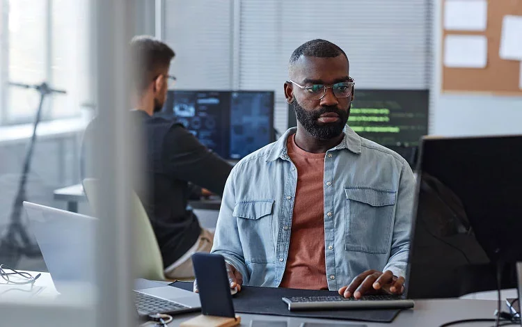 Security professional reviewing data on computer in modern workspace.