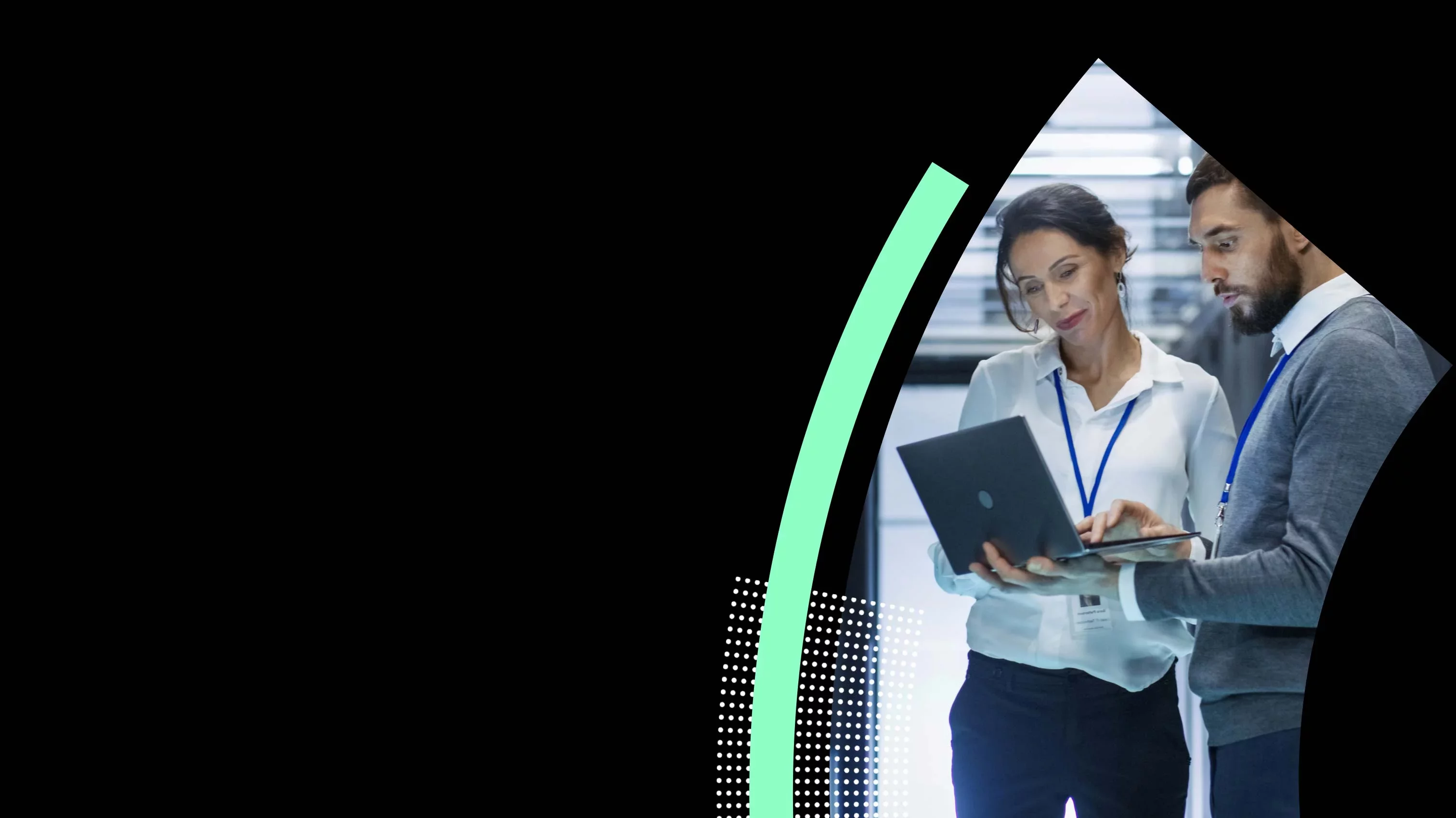 Two professionals reviewing data on laptop in secure data center.